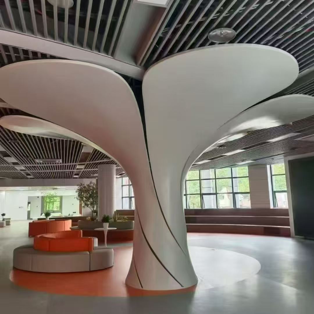 White sculptural column cladding branching into curved ceiling features in a bright lounge with orange seating