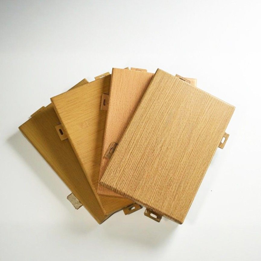 Overlapping aluminum panel samples in light and golden wood-grain finishes with folded edges and mounting tabs