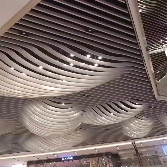 Silver curved ceiling baffles forming flowing waves in a shopping interior