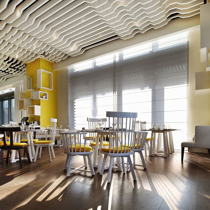 White baffles with stepped lower edges over a sunlit restaurant