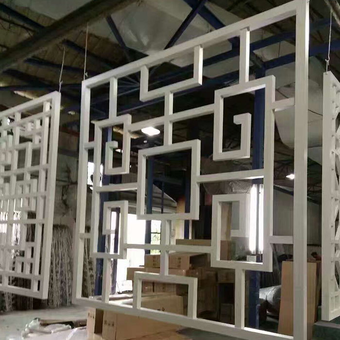 White open geometric grille panels suspended in a fabrication workshop